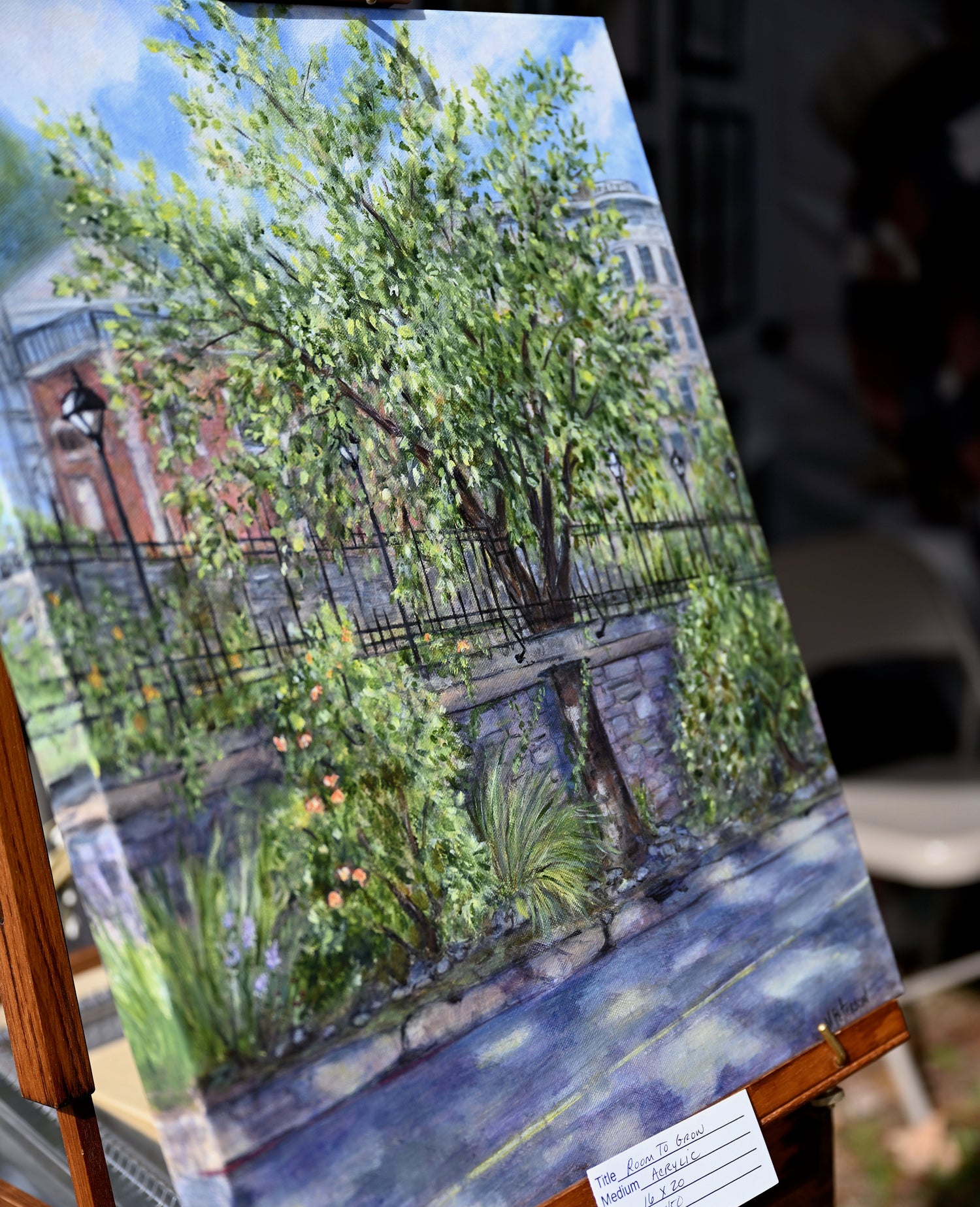 Painting entitled "Room to Grow" is a large tree growing through the sidewalk between two streets